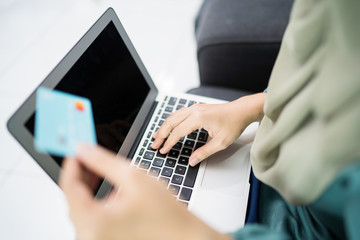 Obraz na płótnie Canvas Female muslim woman using laptop while holding credit card.