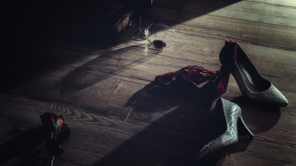Low key photography of red wine glasses and rose with high heel and panties thrown on the floor  romantic erotic lovers night - obrazy, fototapety, plakaty
