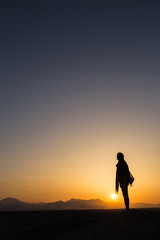 women sihouette with long scarf during sunset in desert in Yazd, Iran