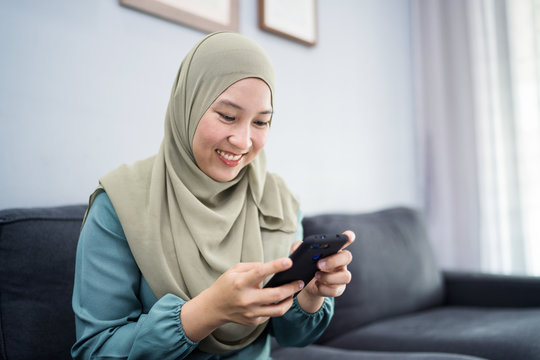 Beautiful muslim woman using her mobile device with facial expression.