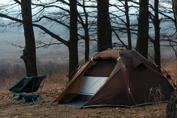 Equipped camp in the forest. Camping tent and portable chairs and aluminum table. Cold autumn day. concept of vacation and outdoor activities. without people. space for text. bonfire
