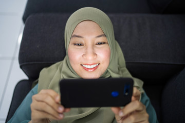 Beautiful muslim woman using her mobile device with facial expression.