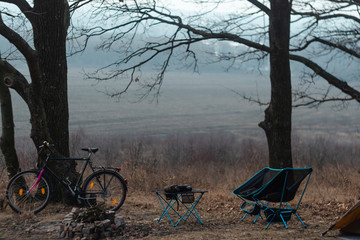 Camping chairs and portable table, lightweight and compact travel items. equipped camp. autumn forest. cool day. bicycle. firewood near the bonfire in the forest.