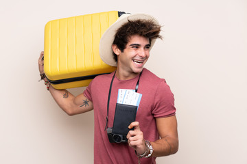 Young caucasian man over isolated background in vacation with suitcase and passport