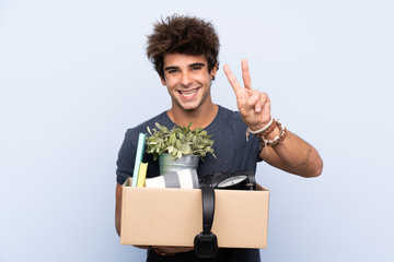 Man making a move while picking up a box full of things smiling and showing victory sign