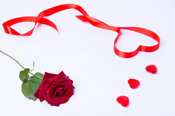 Red rose, ribbon and hearts on a white background. Valentine's Day, Birthday, Mother's Day, International Women's Day. Close-up, selective focus.