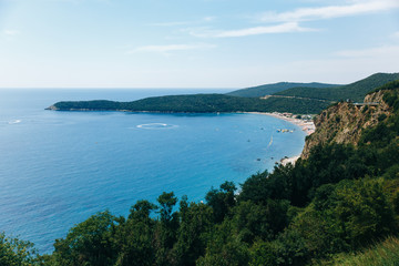 view of the sea bay with a long beach and lots of green trees around