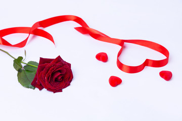 Red rose, ribbon and hearts on a white background. Valentine's Day, Birthday, Mother's Day, International Women's Day. Close-up, selective focus.