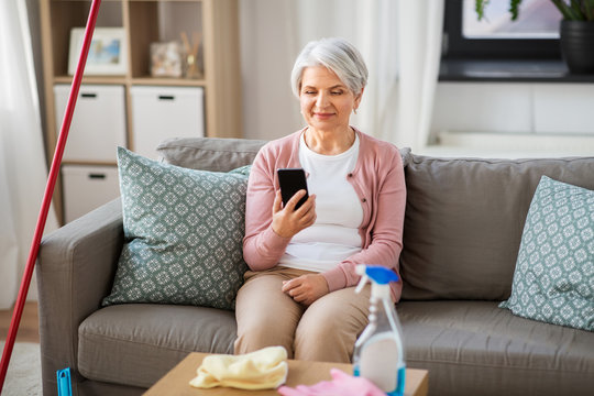 household and technology concept - happy senior woman using smartphone after cleaning home - Powered by Adobe