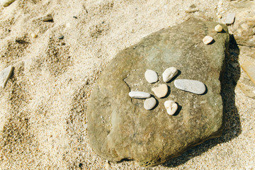 sea stones laid out on stone flower on the beach
