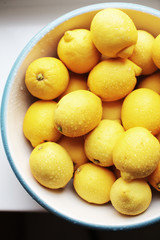 yellow lemons in a glass bowl on wooden background