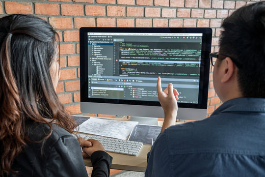 Two professional programmer cooperating and working on web site project in a software developing on desktop computer at company, codes and typing data code, Programming with HTML, PHP and javascript