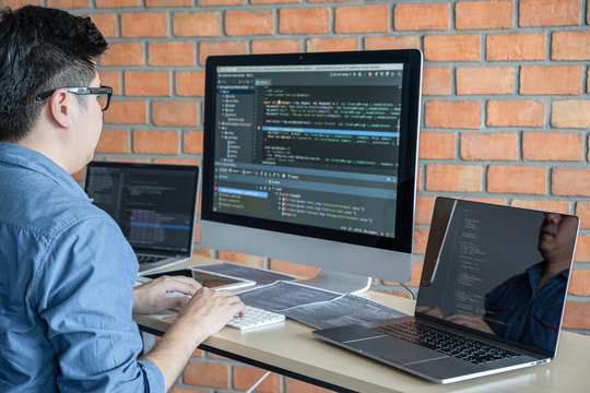 Young Professional programmer working at developing programming and website working in a software develop company office, writing codes and typing data code, Programming with HTML, PHP and javascript
