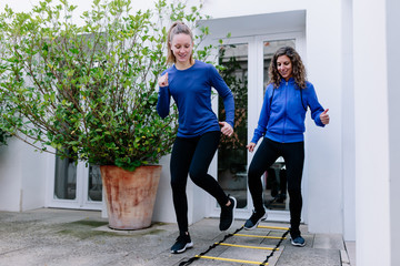 Obraz premium Two young women doing agility ladder exercise on a terrace