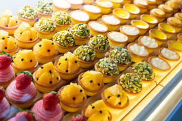 Obraz premium Various flavors of fruit mini pie desserts being displayed inside a transparent glass cabinet