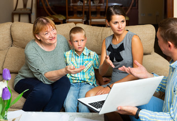 Family looking at laptop and listening to father