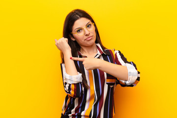 young pretty woman looking impatient and angry, pointing at watch, asking for punctuality, wants to...