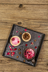 Trendy colored latte. Rose petals and powdered aromatic sugar, coffee beans. Wooden boards background