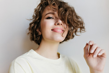 Ecstatic laughing girl posing with happy smile on white background. Indoor close-up photo of glad...