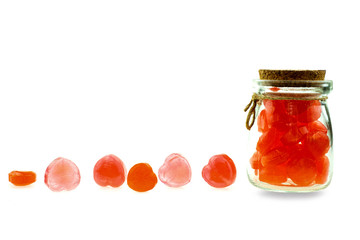 Red heart shaped lollipops together in glass bottle on white background