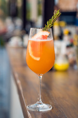 Closeup glass of cocktail decorated with orange at bar background