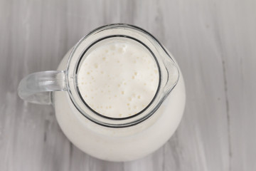 Milk in white ceramic jug isolated on grey background, top view and empty space for text