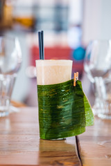 Close-up of banana milk smoothie with drinking straws served in a tall glass.