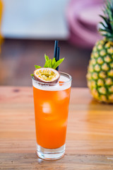 Close-up of passion fruit hurricane fresh cocktail in a tall glass at bar background.