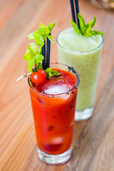 Contrast image of bloody mary cocktail alcoholic drink and green healthy mint smoothie.
