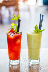 Contrast image of bloody mary cocktail alcoholic drink and green healthy mint smoothie.