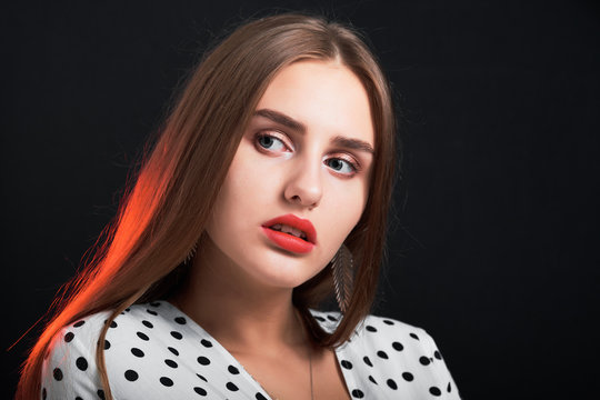 Portrait of a young attractive girl with long hair and red lips against black background.