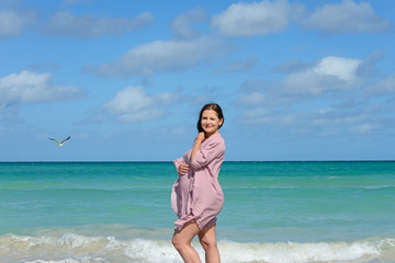 Fototapeta na wymiar Pregnant caucasian brunette woman stands on the shore of the Atlantic ocean at midday, Cuba