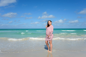 Pregnant caucasian brunette woman  stands on the shore of the Atlantic ocean at midday, Cuba