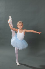 Cute little ballerina in tutu in dance studio. Ballerina doing twine.