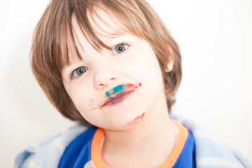Little kid with mounth stained after eating cakes coated with synthetic food colorants
