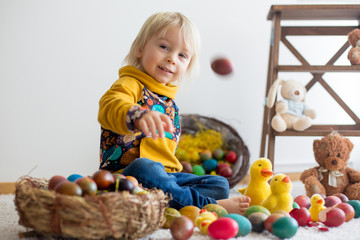 Fototapeta na wymiar Toddler child, blonde boy playing with Easter eggs. Children plays with eggs and chicks