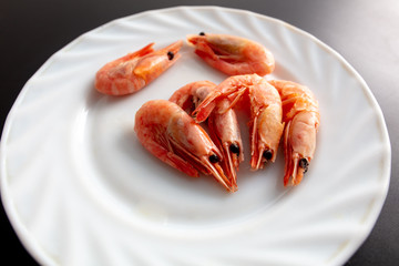 Red shrimp in a white plate on a black