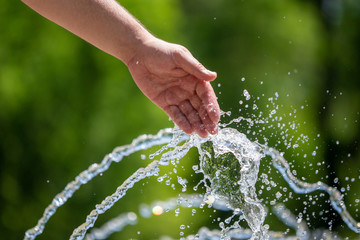 Hand of a man in the spray of water of the fountain