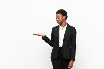 young pretty black womanfeeling happy and smiling casually, looking to an object or concept held on...