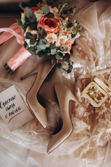 Wedding details in  beige and pink colours. Wedding dress, rings, bouquet, shoes