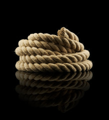 Textured old rope coiled on reflective background.