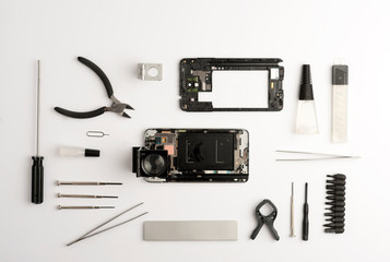 set tools workshop for mobiles, with broken open telephone, screwdrivers, cutter, glue, tweezers, magnifying glass, accessories red, pencil, white background.top view.concept mobile workshop