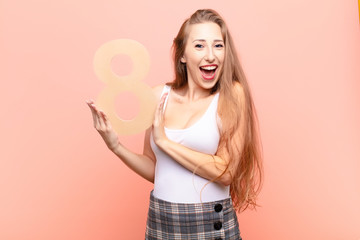 yound blonde woman excited, happy, joyful, holding a number 8.