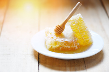 Fresh Honey , Honey Bee healthy food yellow sweet honeycomb slice with wooden dipper on white plate wood background