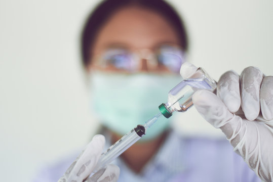 Syringe medication injection and needle in hand nurse for giving patient vaccine prophylactic - Medication drug bottle equipment medical liquid drug , African american female doctor