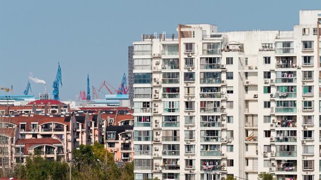 Time lapse video of Shanghai apartment buildings with chimney and harbor background at sunny afternoon, 4k footage.