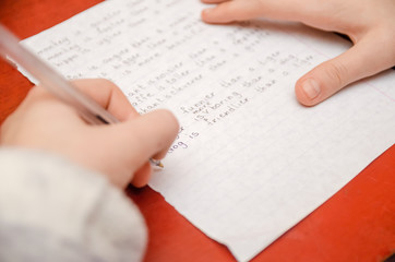 girl does a task in English, writes in a notebook close-up