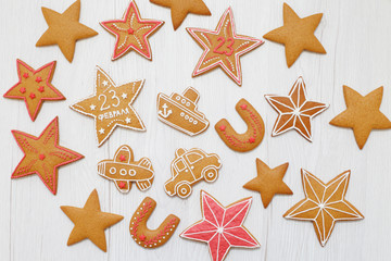 Homemade Gingerbreads in the form of stars, ship, airplane, car and number "23" on Defender of the Fatherland Day on wooden background