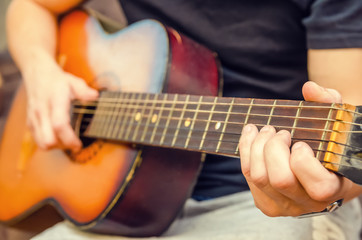 Fototapeta na wymiar man plays a brown guitar in close-up