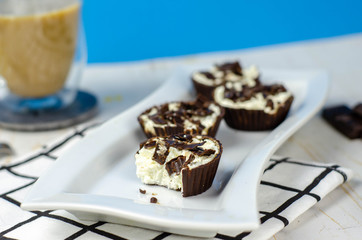 Mini homemade cheesecakes in chocolate baskets and coffee with milk for breakfast, sugar free dessert, healthy food, proper nutrition